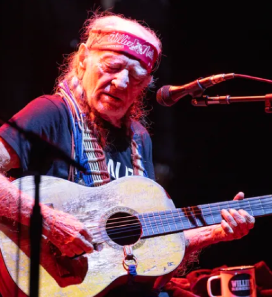 Photo of Willie Nelson performing at Outlaw Music Festival